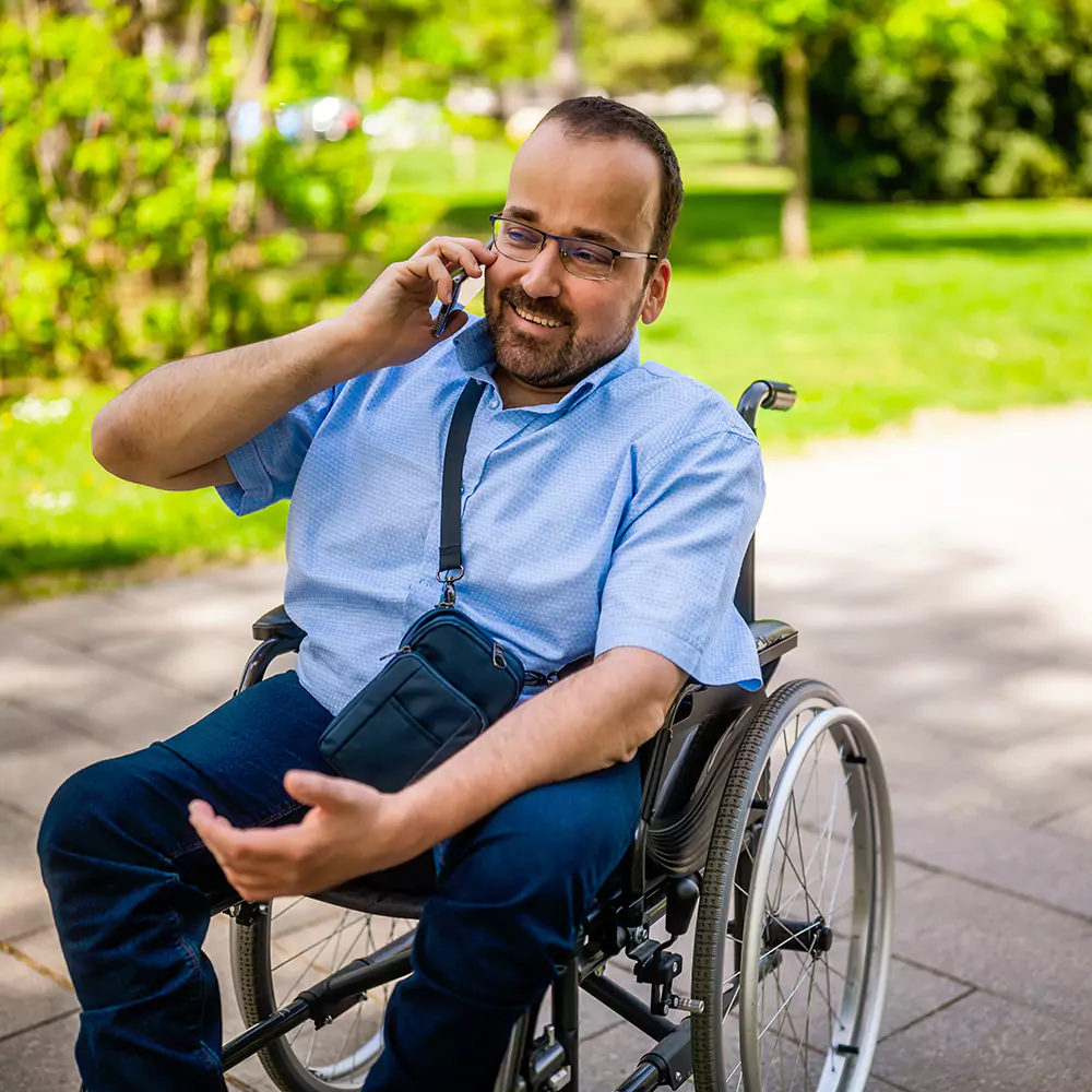 Disabled man in wheelchair using mobile phone to make phone call